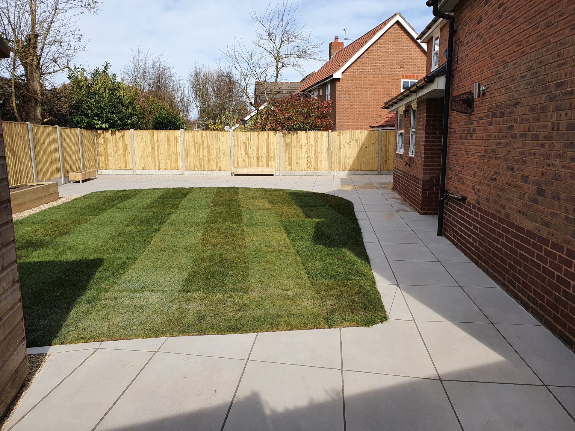 Light coloured slabbed landscaped garden, raised borders and fencing