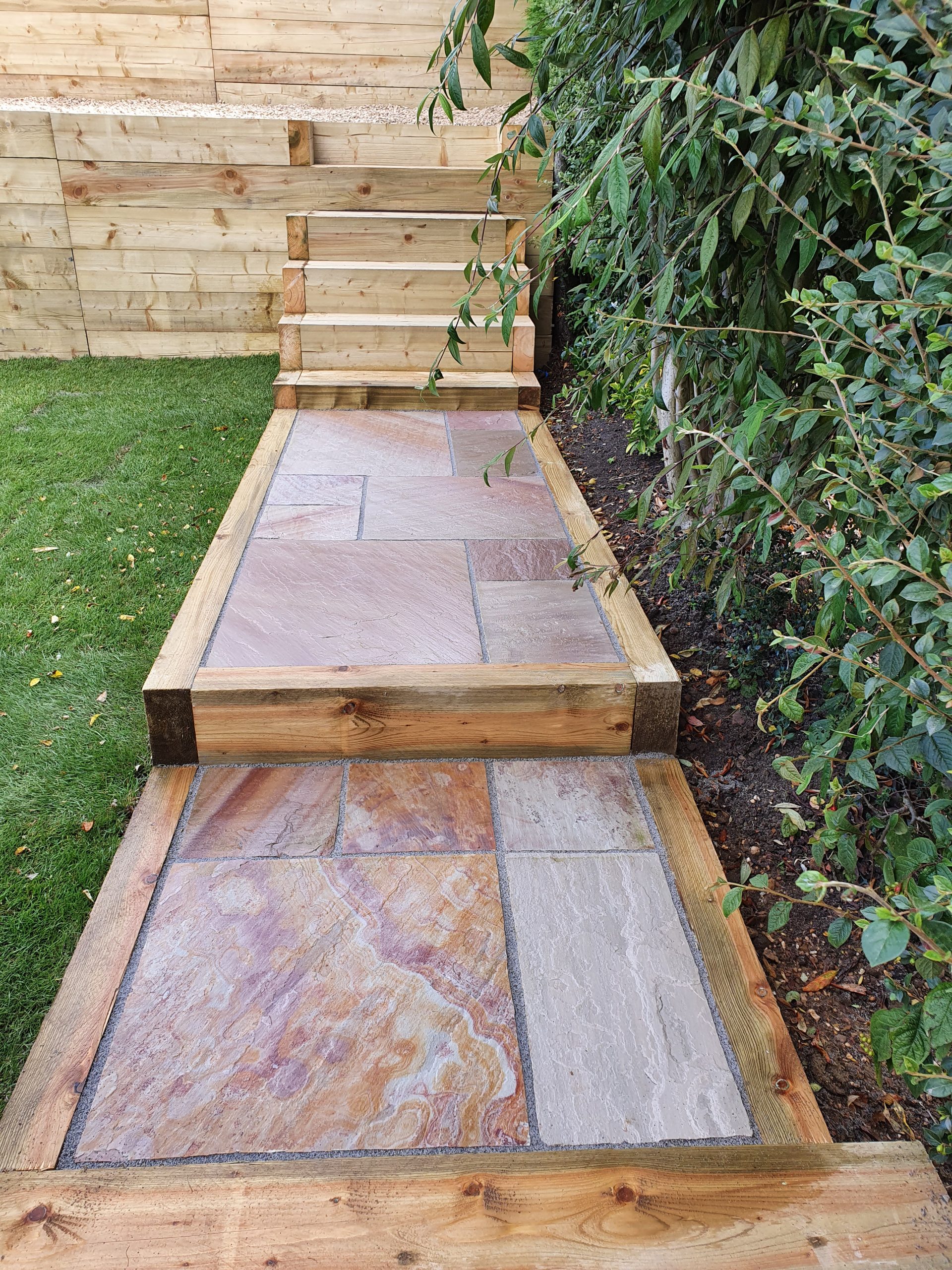 Tiered multi level garden wooden sleeper retainer walls, steps and newly laid turf
